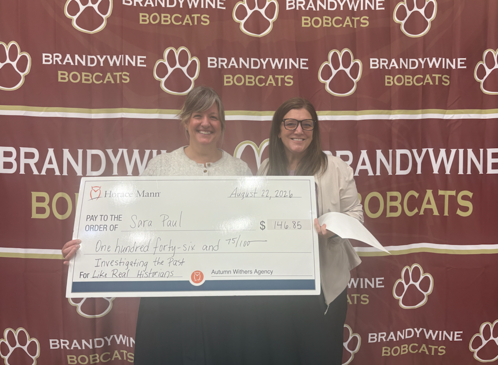 teacher and presenter with large check