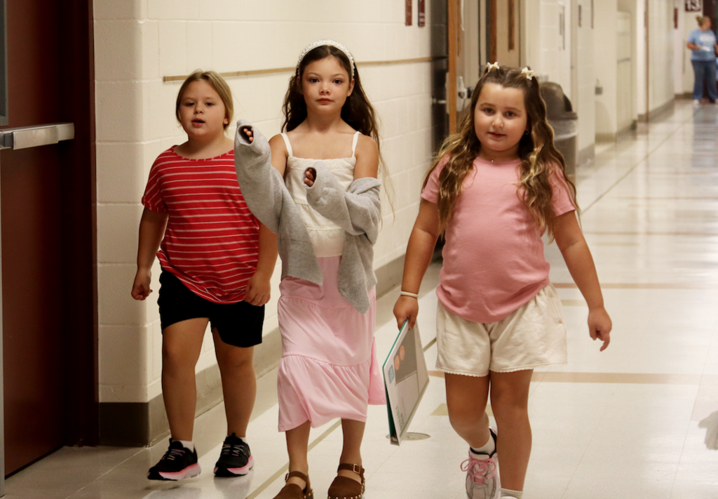 three little girls walking down the hallway