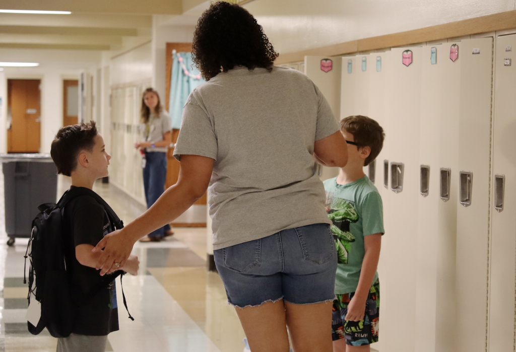 a teacher helping two little boys in the hallway