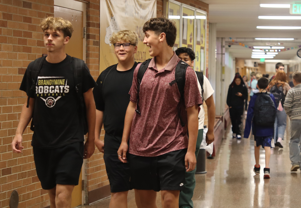 three boys smiling and laughing walking down the hallway