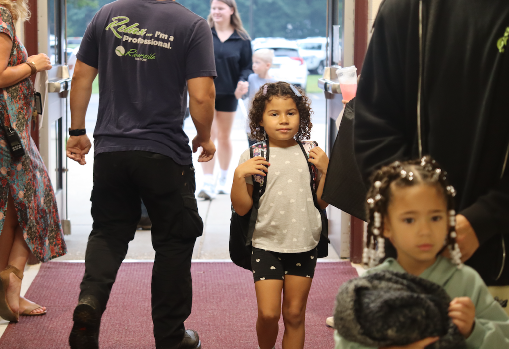 little girl with backpack walking into the school