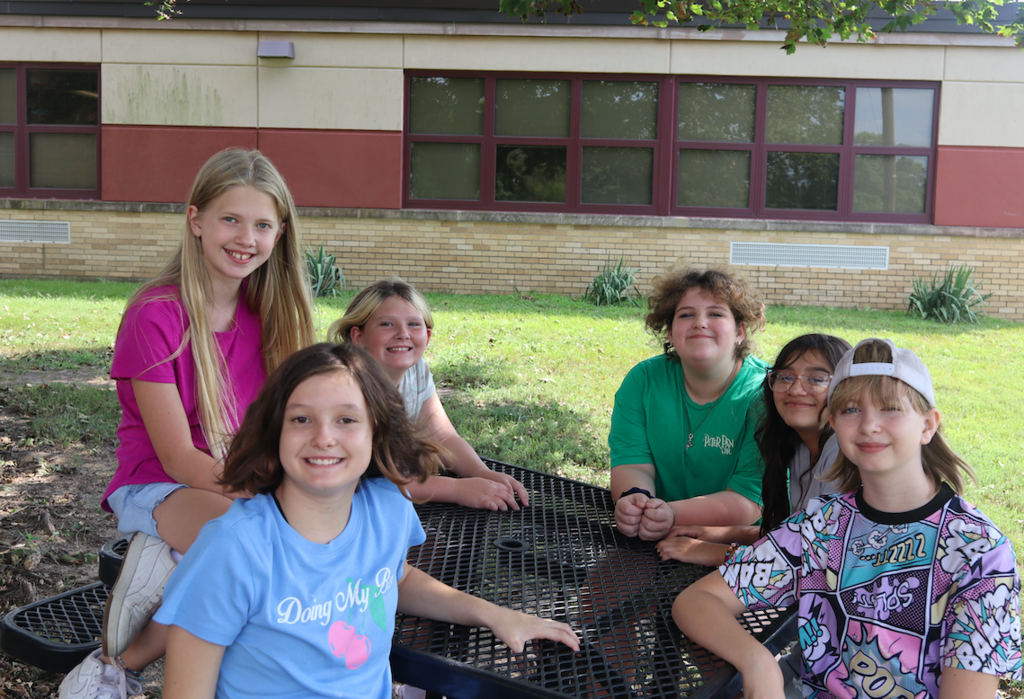 6 girls sitting at a table at recess