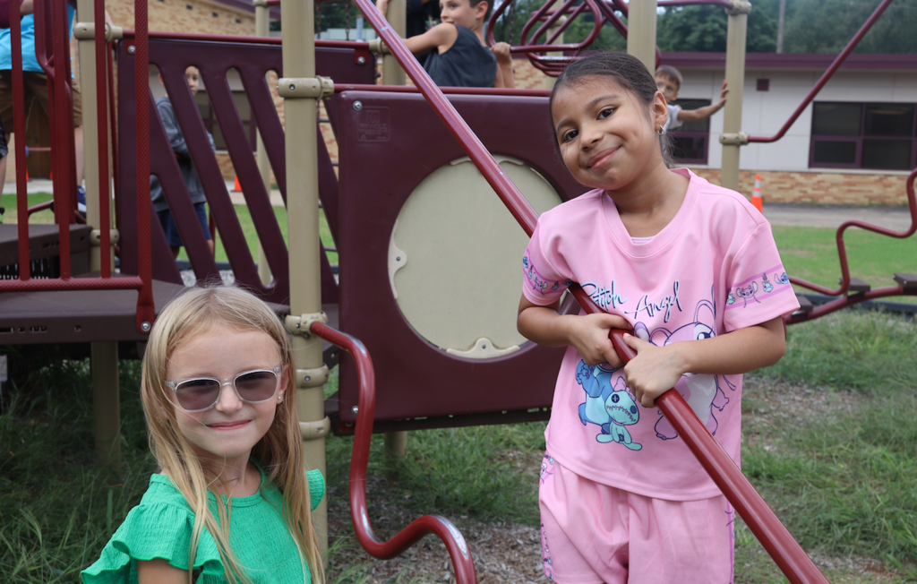 two girls smiling at the camera on playground