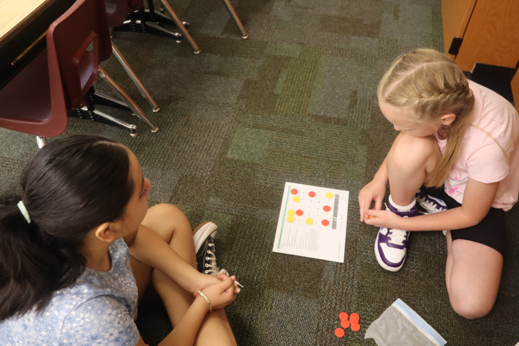 two girls on the ground working on math card