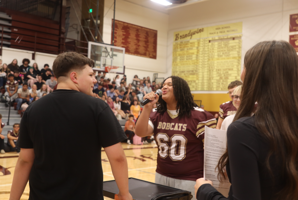 male student singing, wearing football jersey