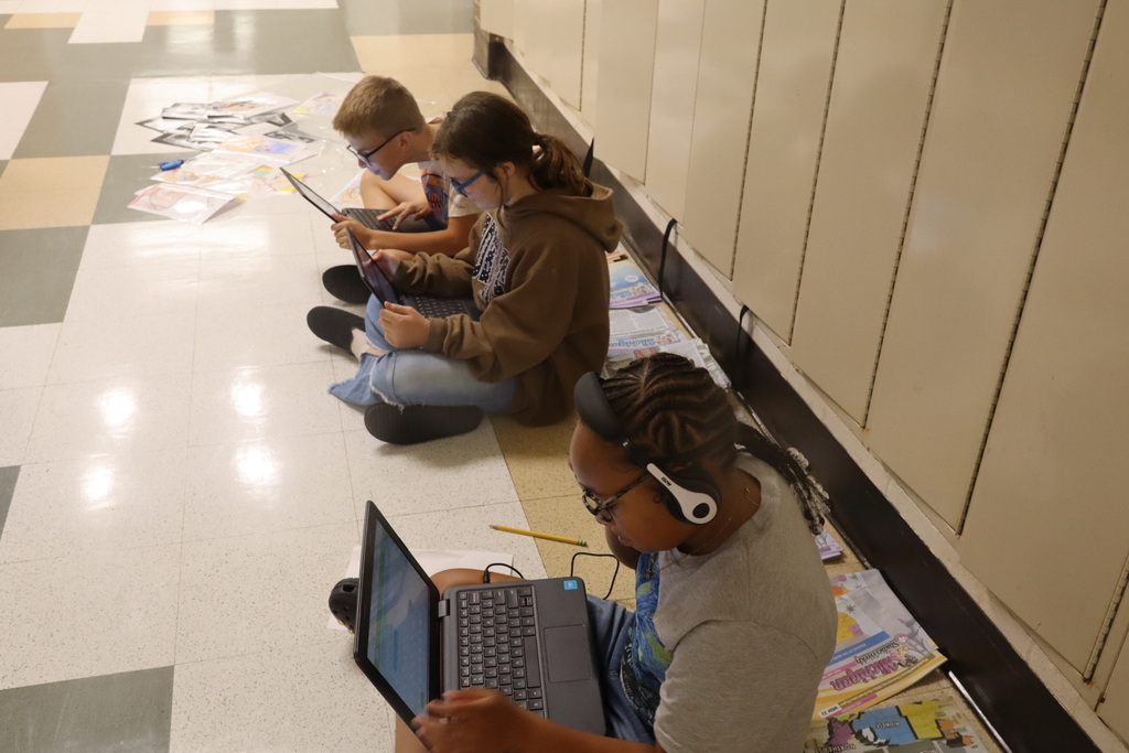 three studenst working on a computer with headphones on
