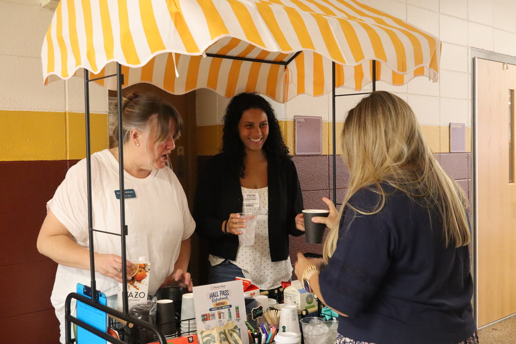 two women serving another woman a coffee at a cart