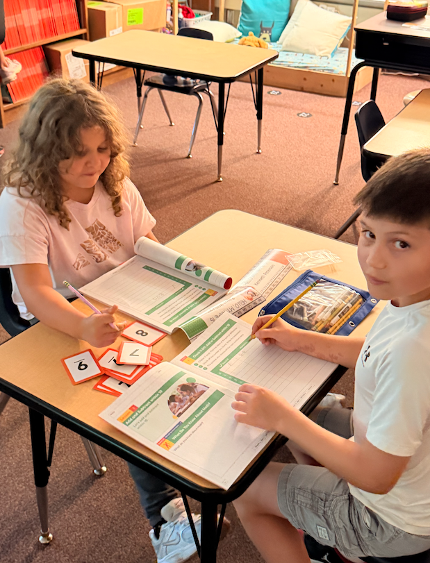 two kids sitting at a desk