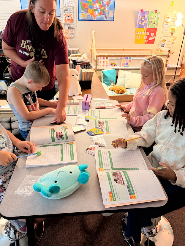 teacher working with students sitting at desk