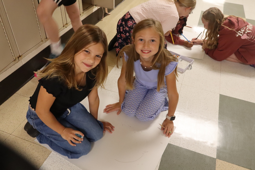 two girls smiling while working on a poster board project