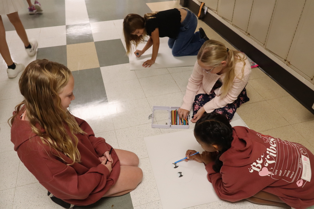 three girls sitting on floor working on poster board