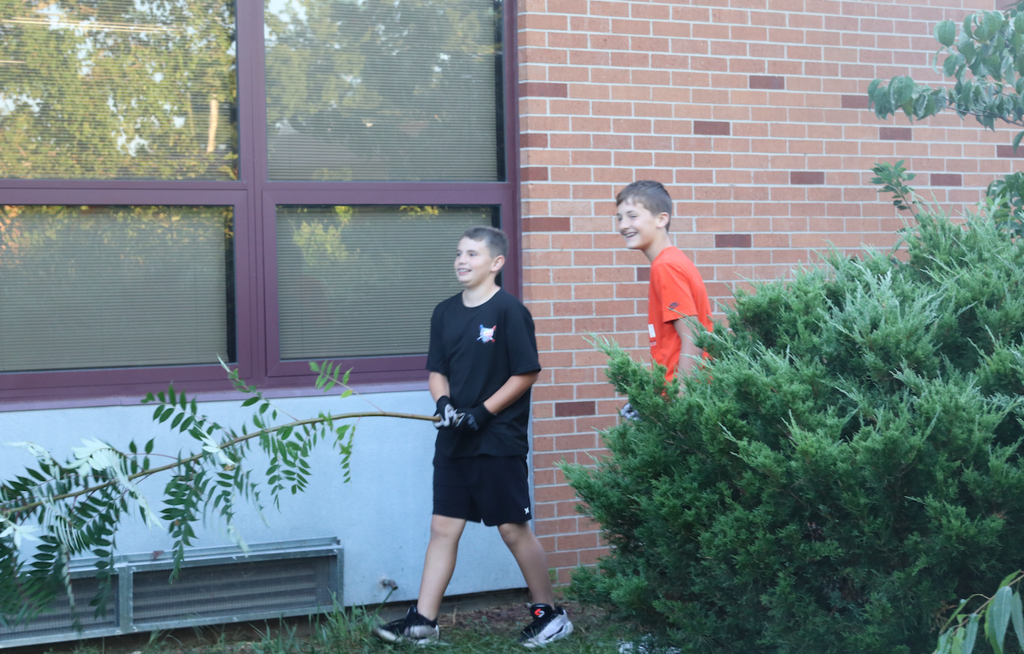 two boys picking up branches in courtyard