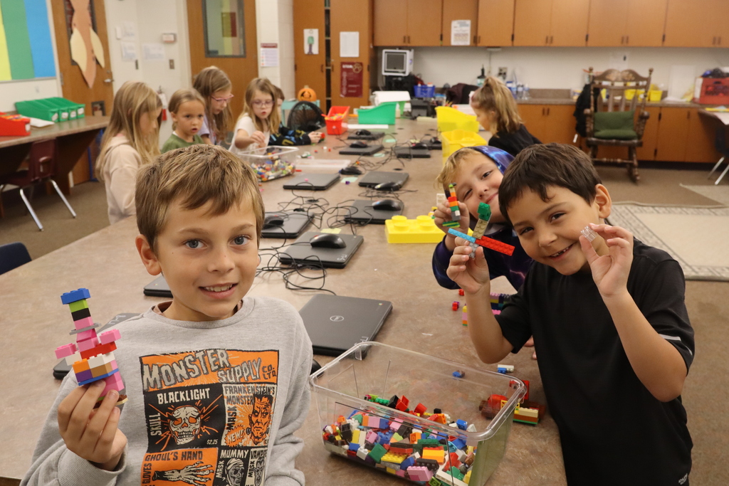 three boys showing off legos they built