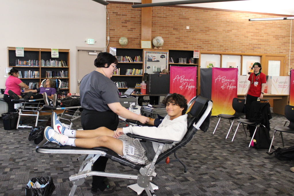 at young man getting his blood donated, sitting in a chair