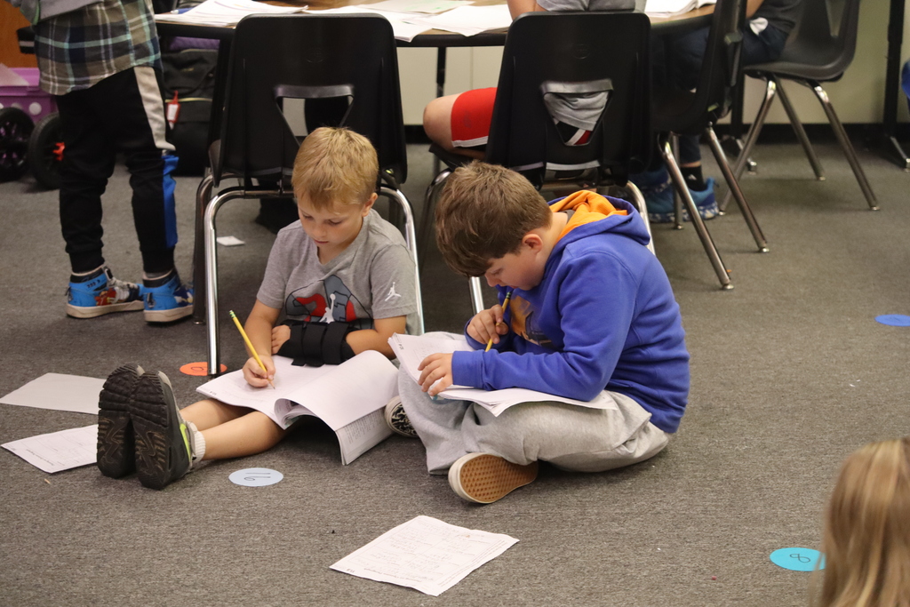 two young boys sitting on the floor doing their work