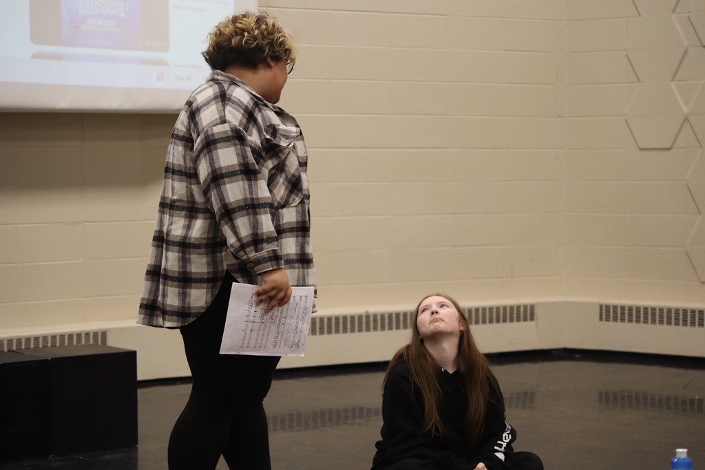 students on stage together, one sitting down 