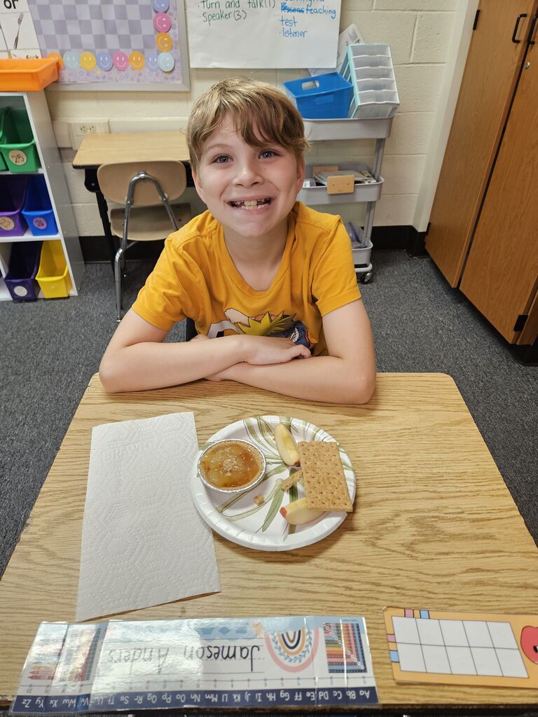 young boy at desk with apple pie on plate