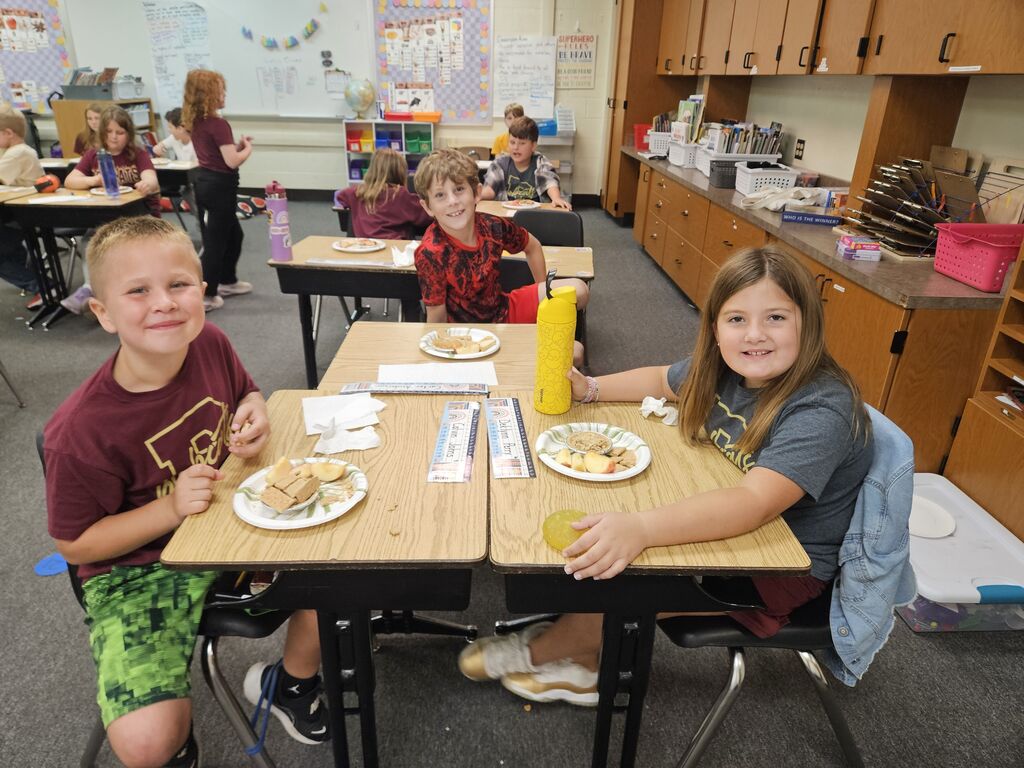 three kids in classroom at their desk with apple pie on their plates