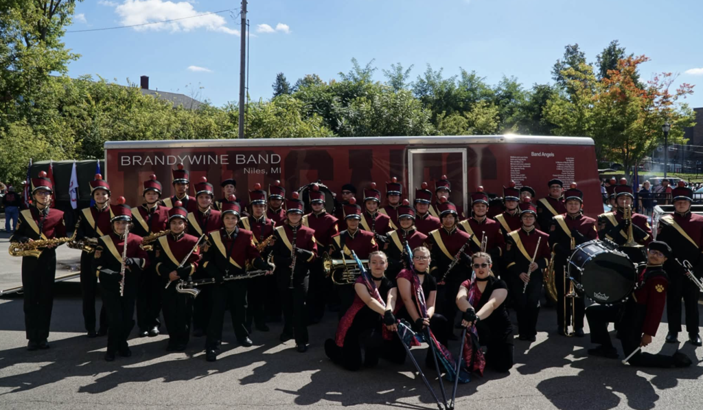 marching band in unfirms in front of trailer