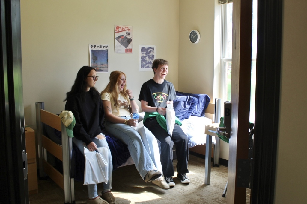 three students in a dorm room laughing