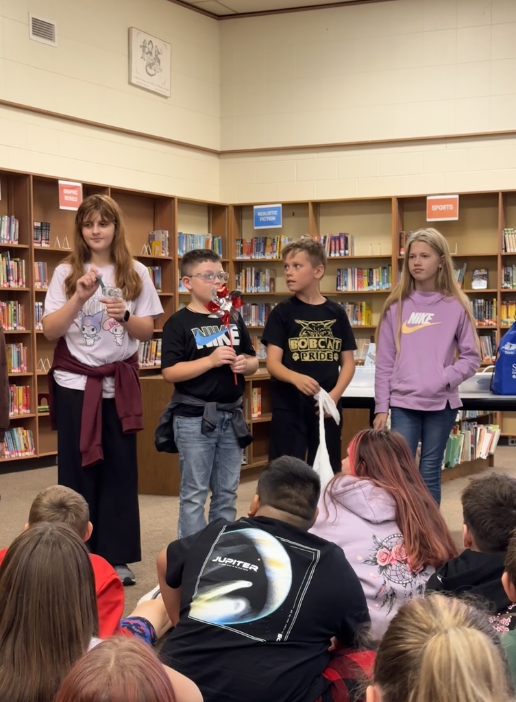 four fifth graders standing at the front of the room