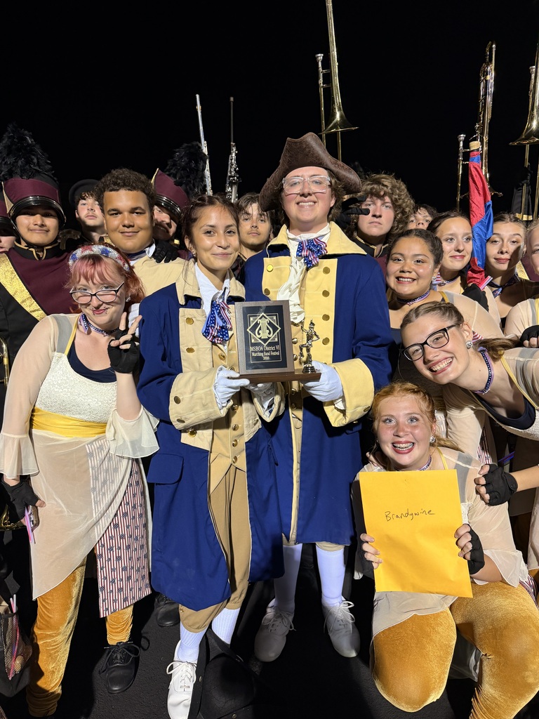 drum majors holding trophy surrounded by band