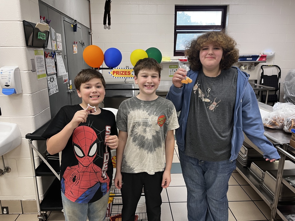 three kids standing in front of balloons holding treats