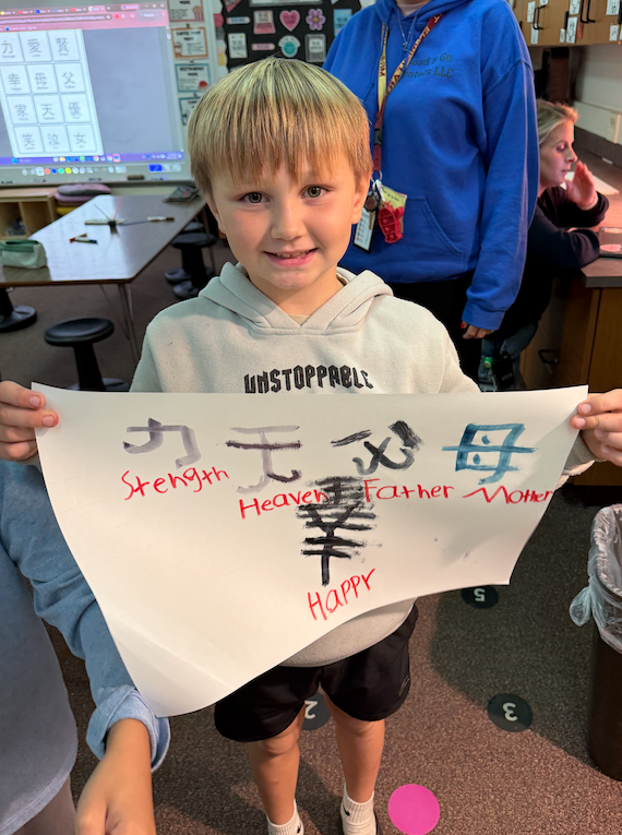 little boy holding paper with chinese character