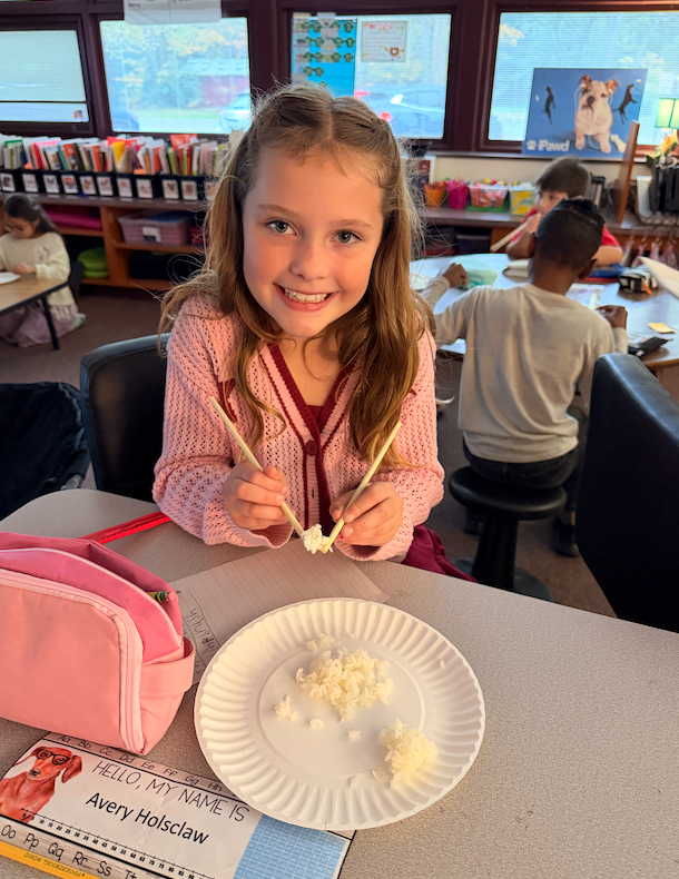 little girl holding rice with chopsticks