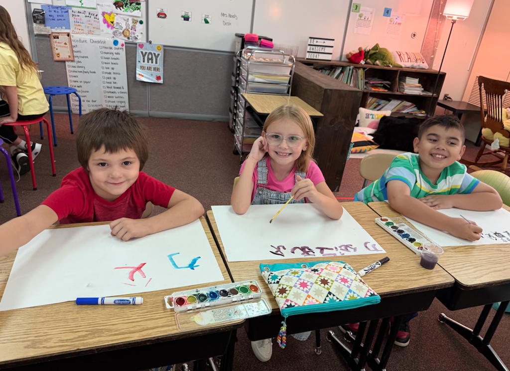three kids at desk writing chinese characters