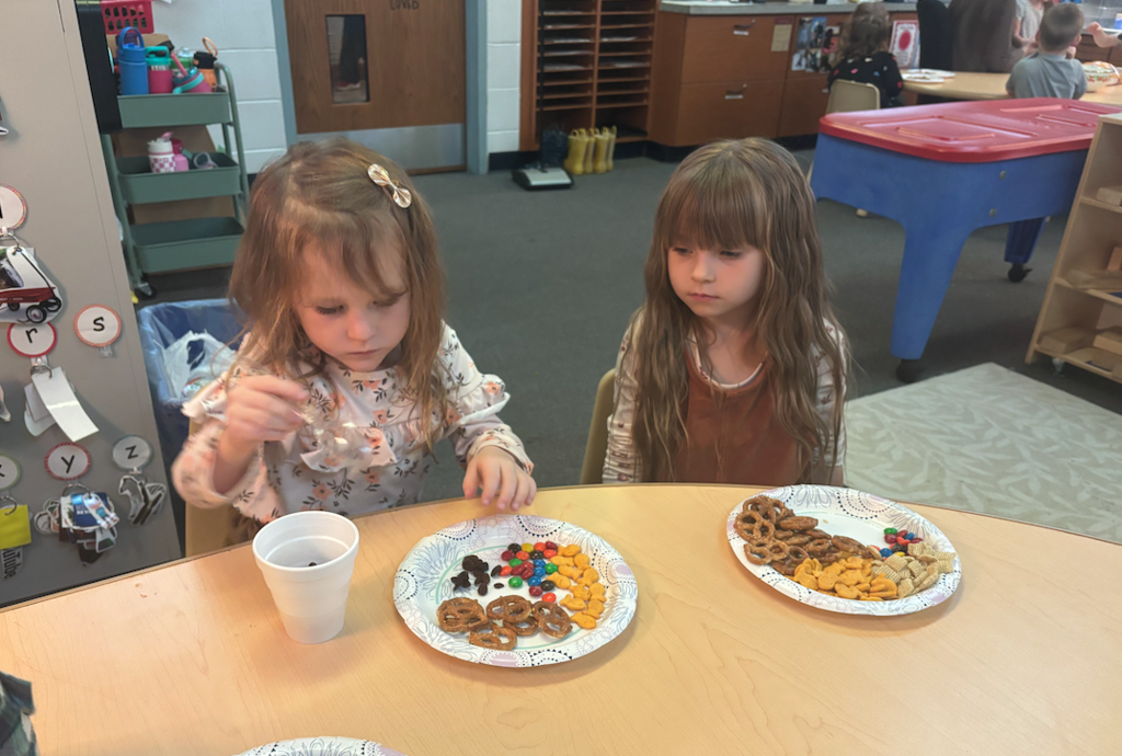 two little girls making trail mix at the table