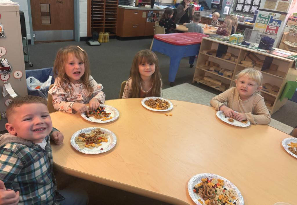 four little kids sitting at the table with their trail mix