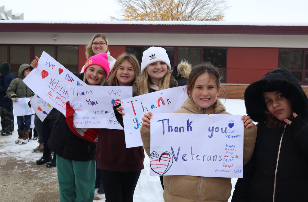 girls standing with thank you veterans signs outside