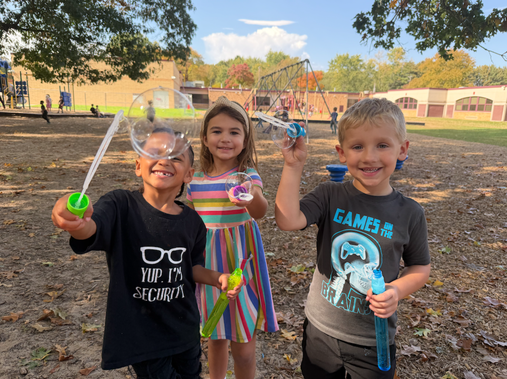 three kids blowing bubbles on the playground