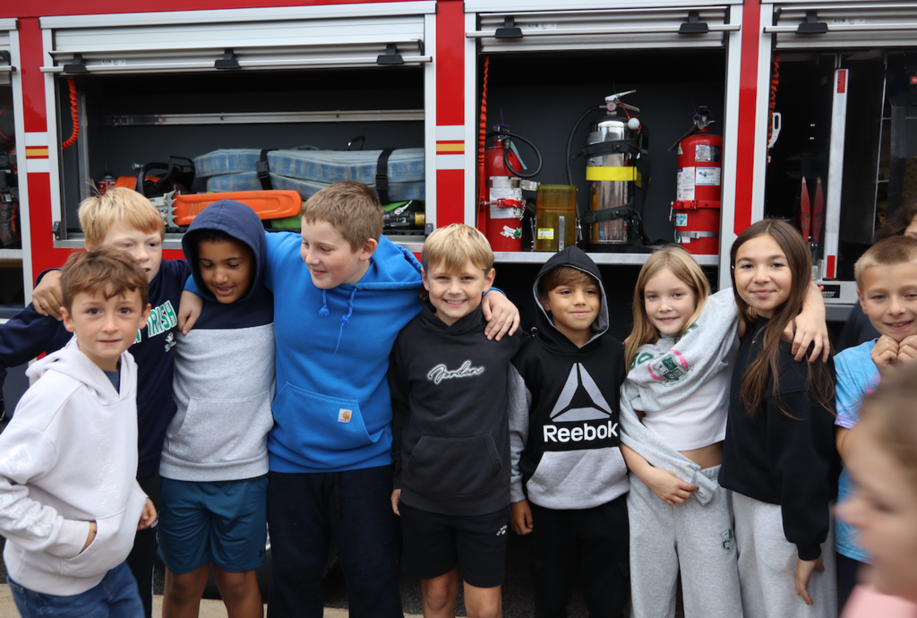 group of students standing next to a firetruck
