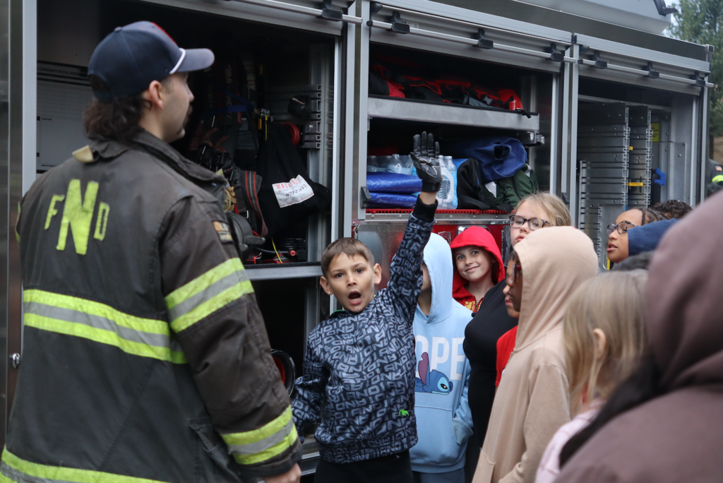 student raising hand to firefighter