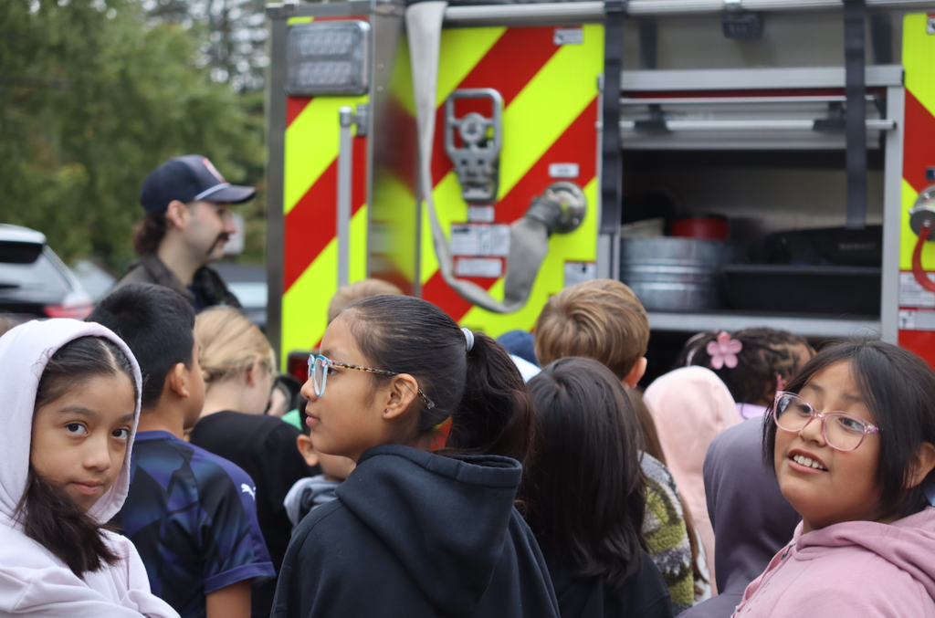 group of students looking at fire truck with firefighter
