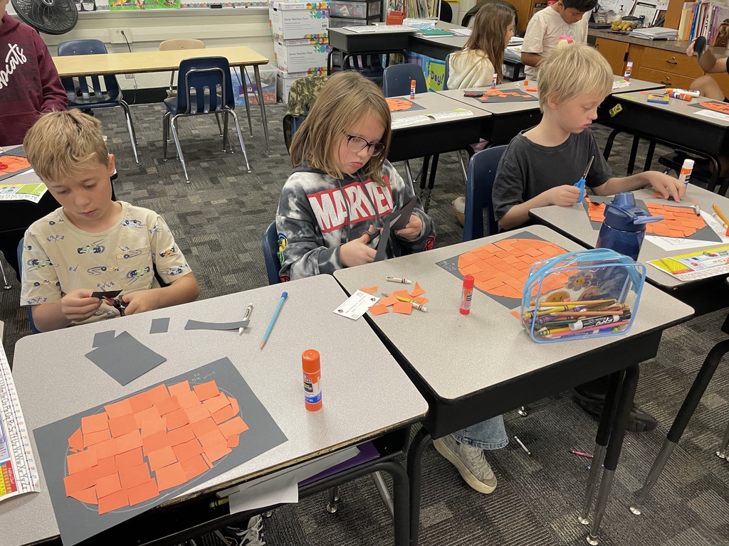 three students at desk creating pumpkins