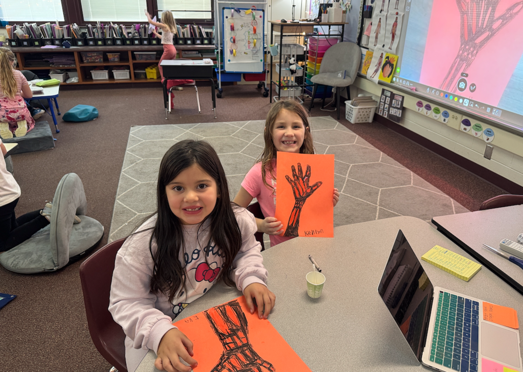 two little girls holding hand drawings