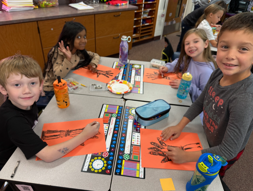 group of kids sitting at desk with hand drawings