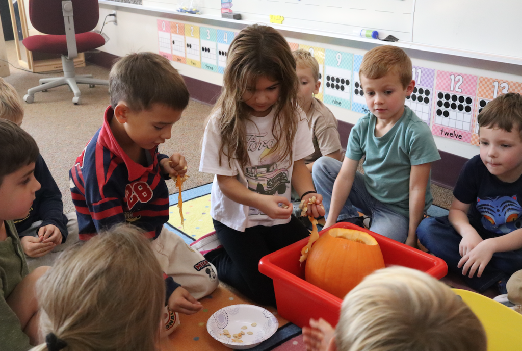 group of kids on floor removing pumpkin seeds from pumpkins