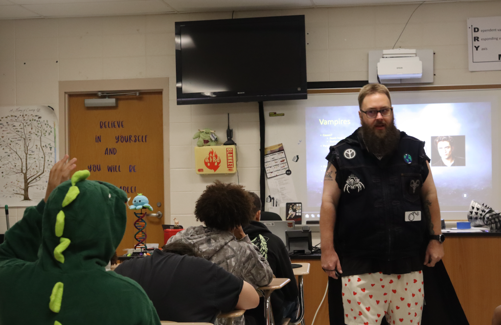 student raising hand, teacher walking around classroom