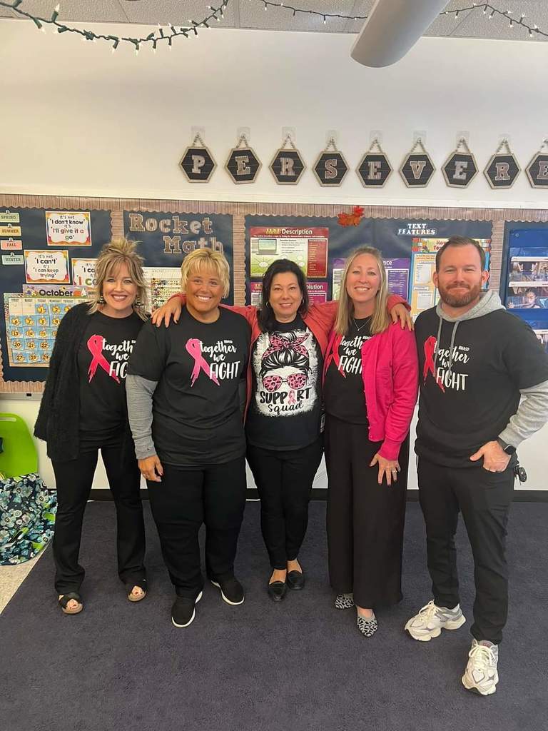 Five teachers pose in a classroom with their breast cancer shirts.
