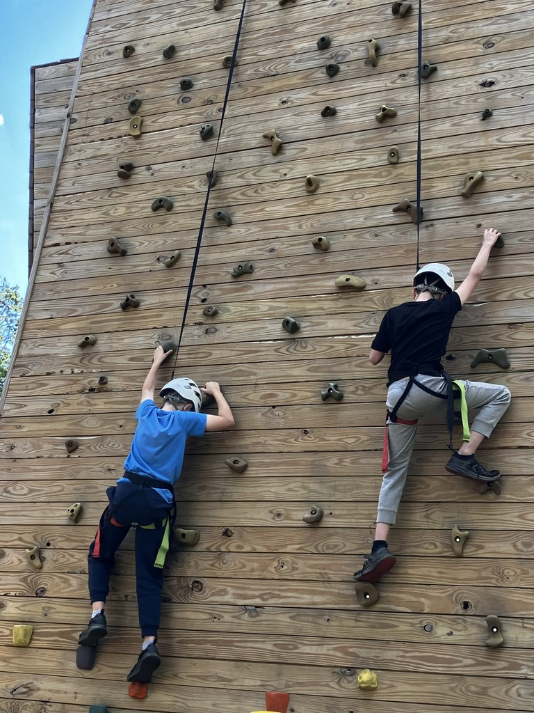 two students climbing the rock wall