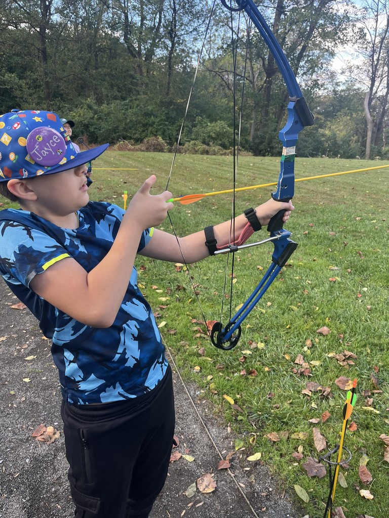 student shoots a bow and arrow at camp