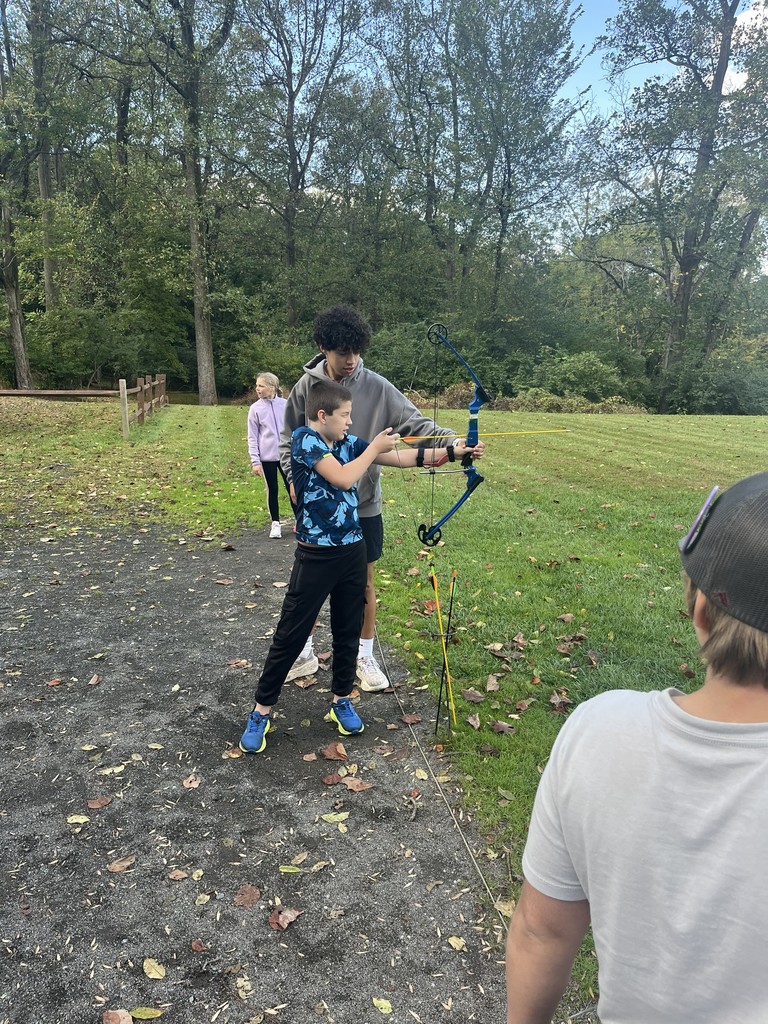 student shoots a bow and arrow at camp