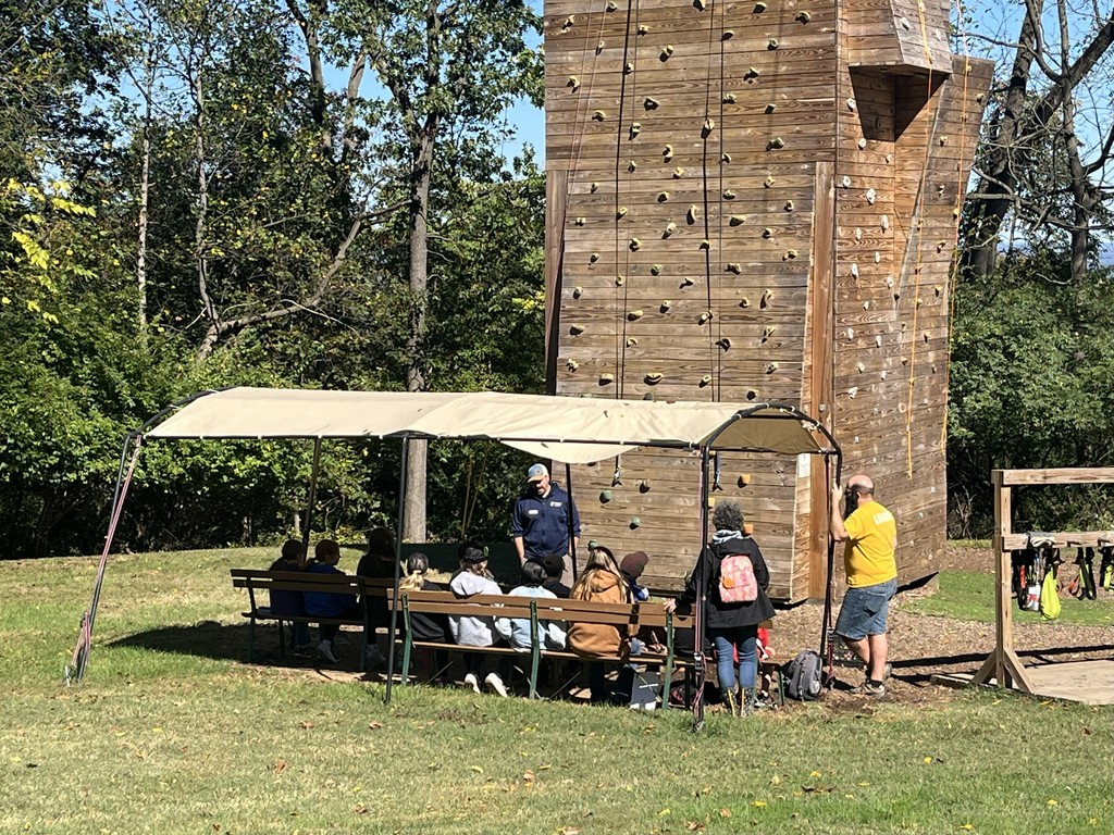 students listen to instructions at the climbing wall