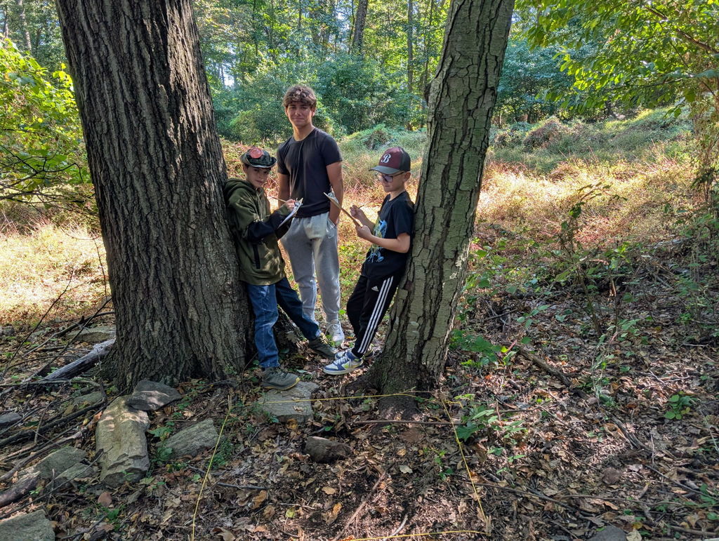 students leaning against trees