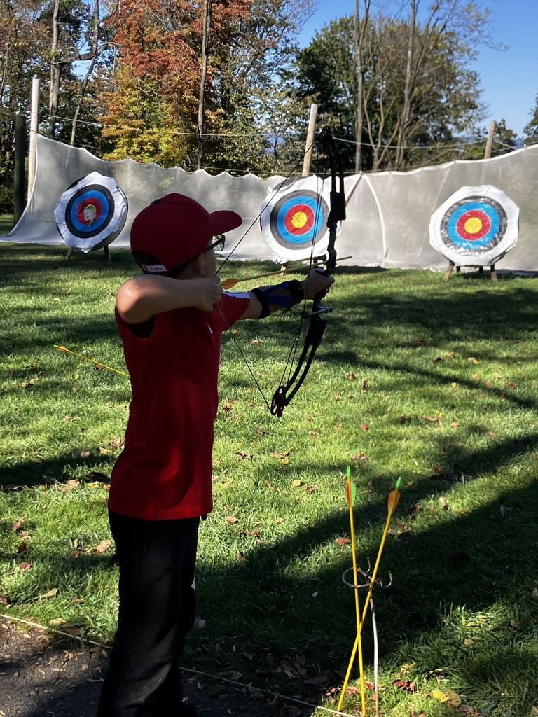 student shooting bow and arrow at a target