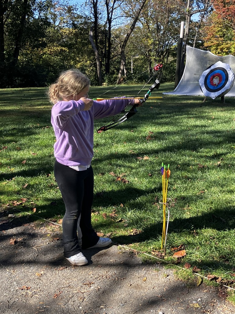 student shooting bow and arrow at a target